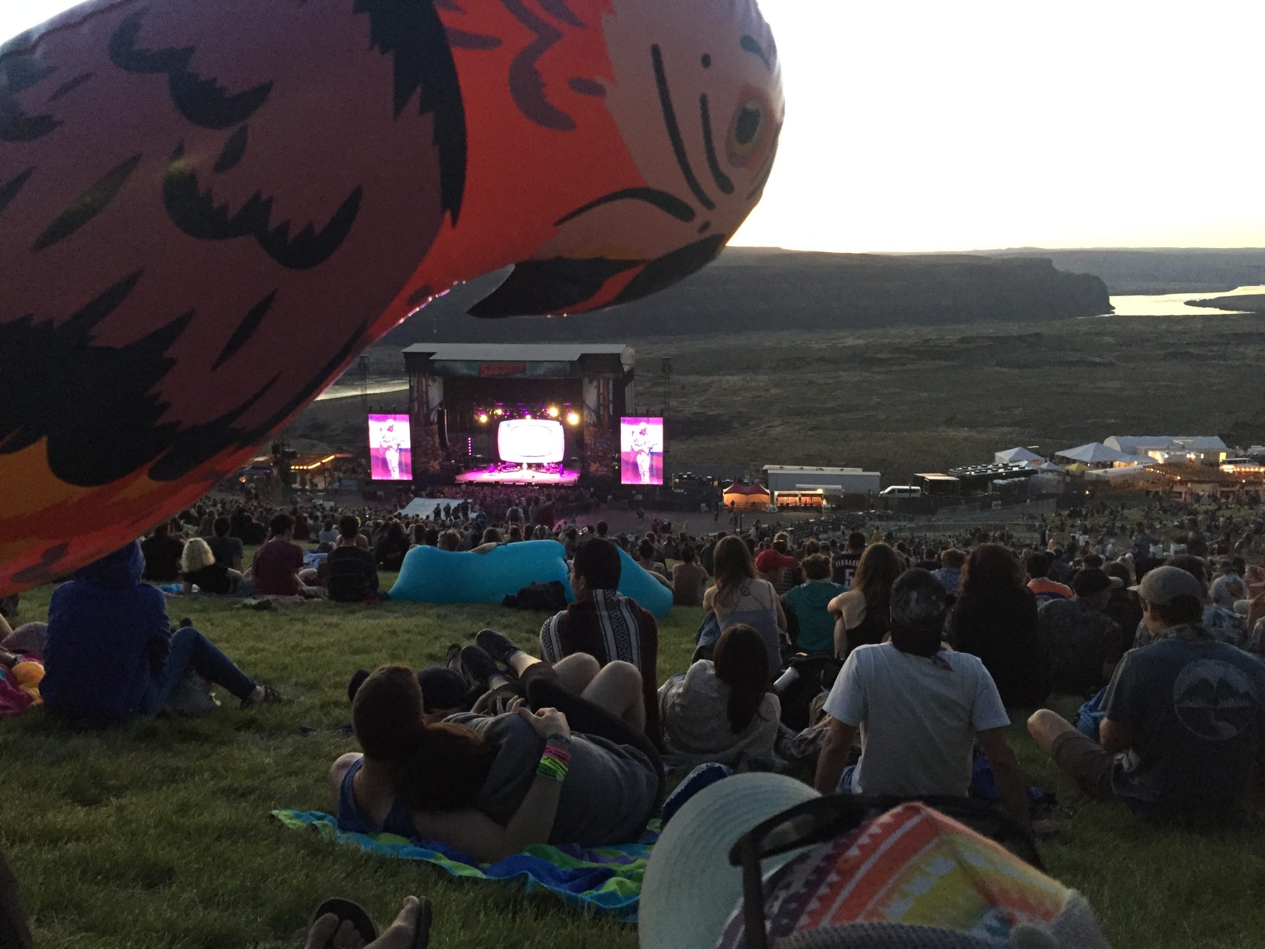 alt="sat on grass looking at main stage The Gorge"