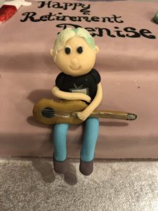 alt="marzipan cake figure of Denise with guitar"