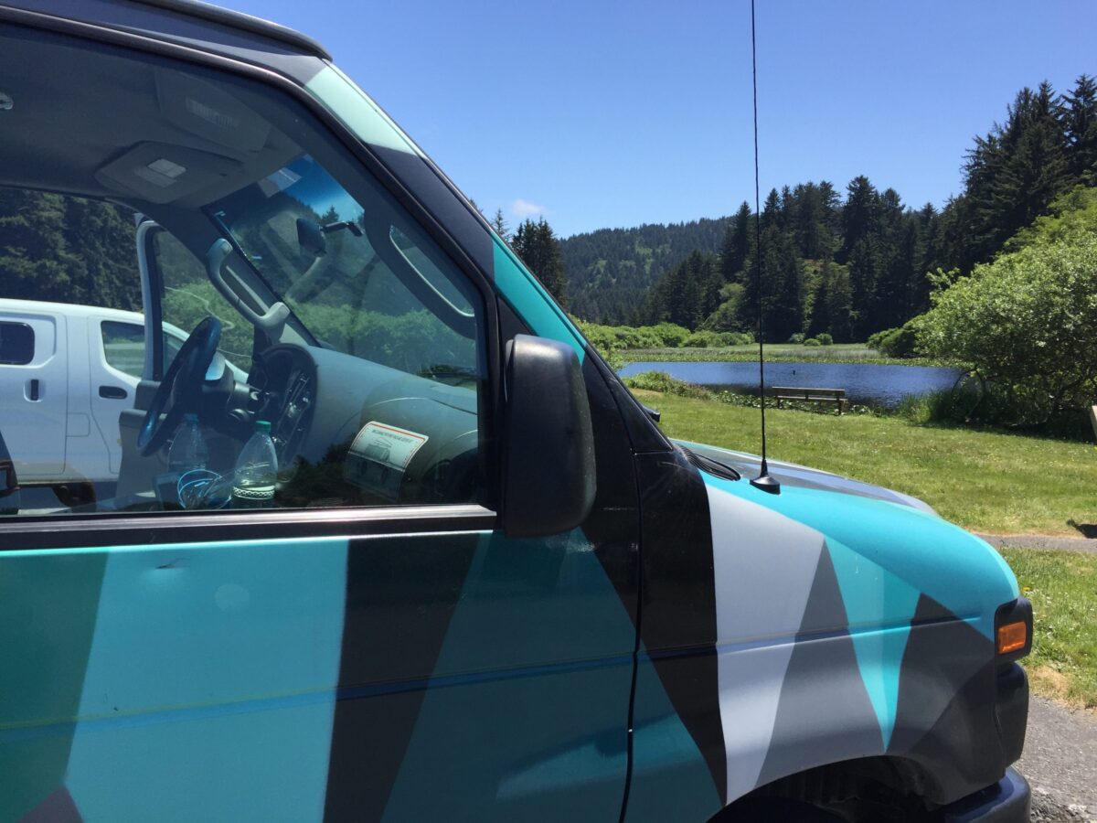 alt="side of a multi coloured camper van with a mosaic pattern"