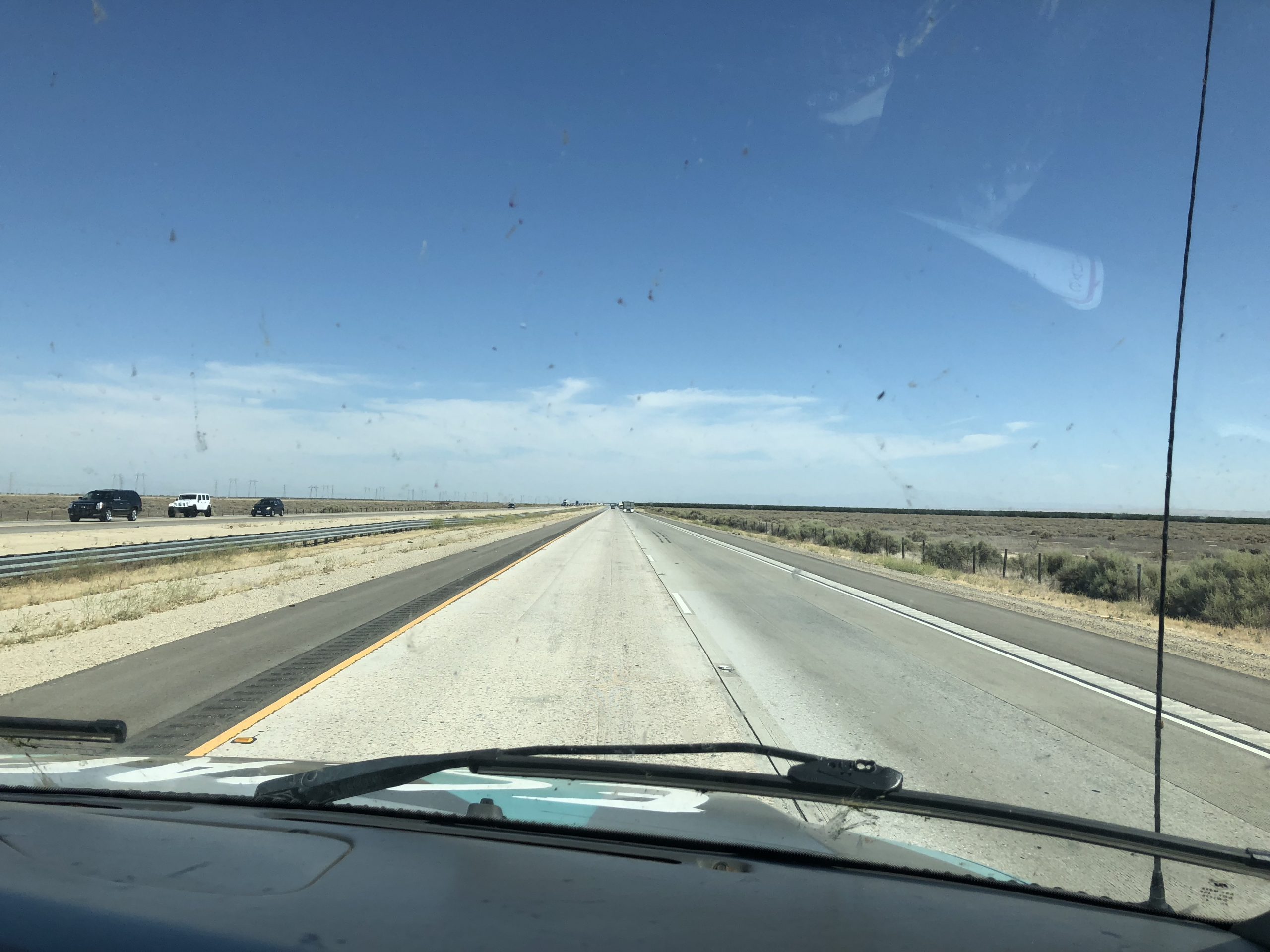 alt="a long empty road stretching ahead as seen from a camper van"