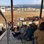 alt="cowboy with truck & spectators seated in the stand"