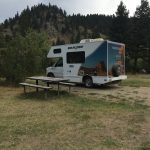 alt=" small rv parked next to a picnic bench"