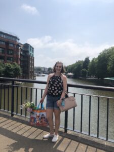 alt="person stood on bridge with shopping"