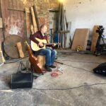 alt="person sat with guitar"