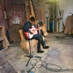 alt="person sat playing guitar"