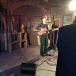 alt="person standing playing guitar"