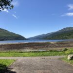 alt="shore with lake & mountains in distance"