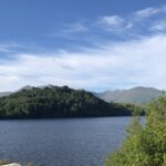 alt="lake with tree covered hill"