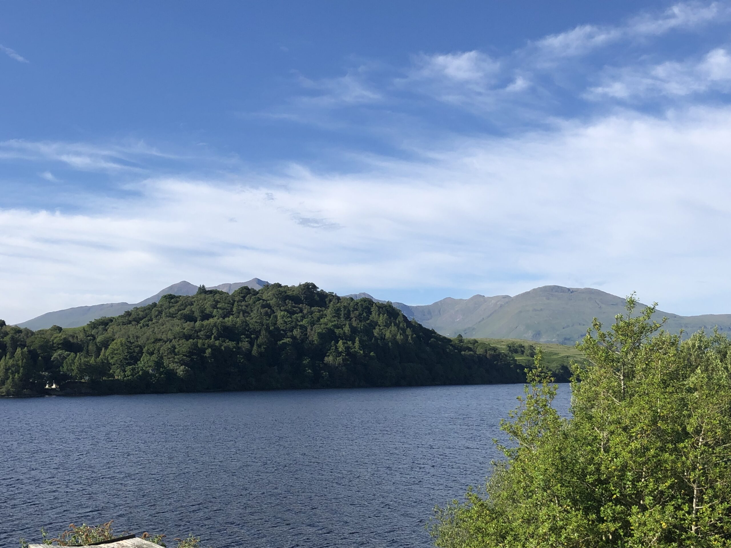 alt="lake with tree covered hill"