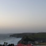 alt="looking from the cliff across the headland & sea"