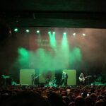 alt="band on stage with crowd & lights"