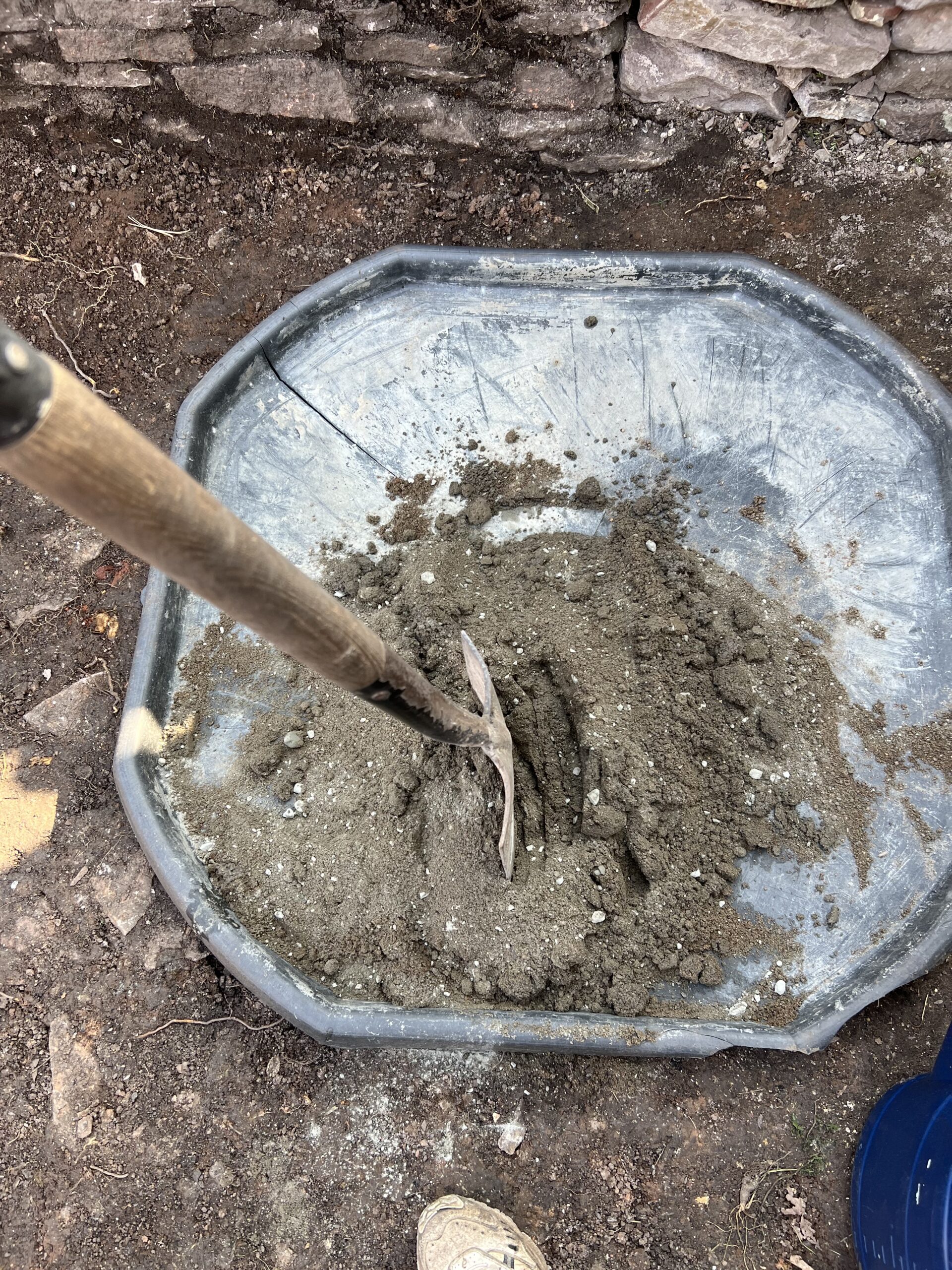alt="shovel mixing cement on a tray"