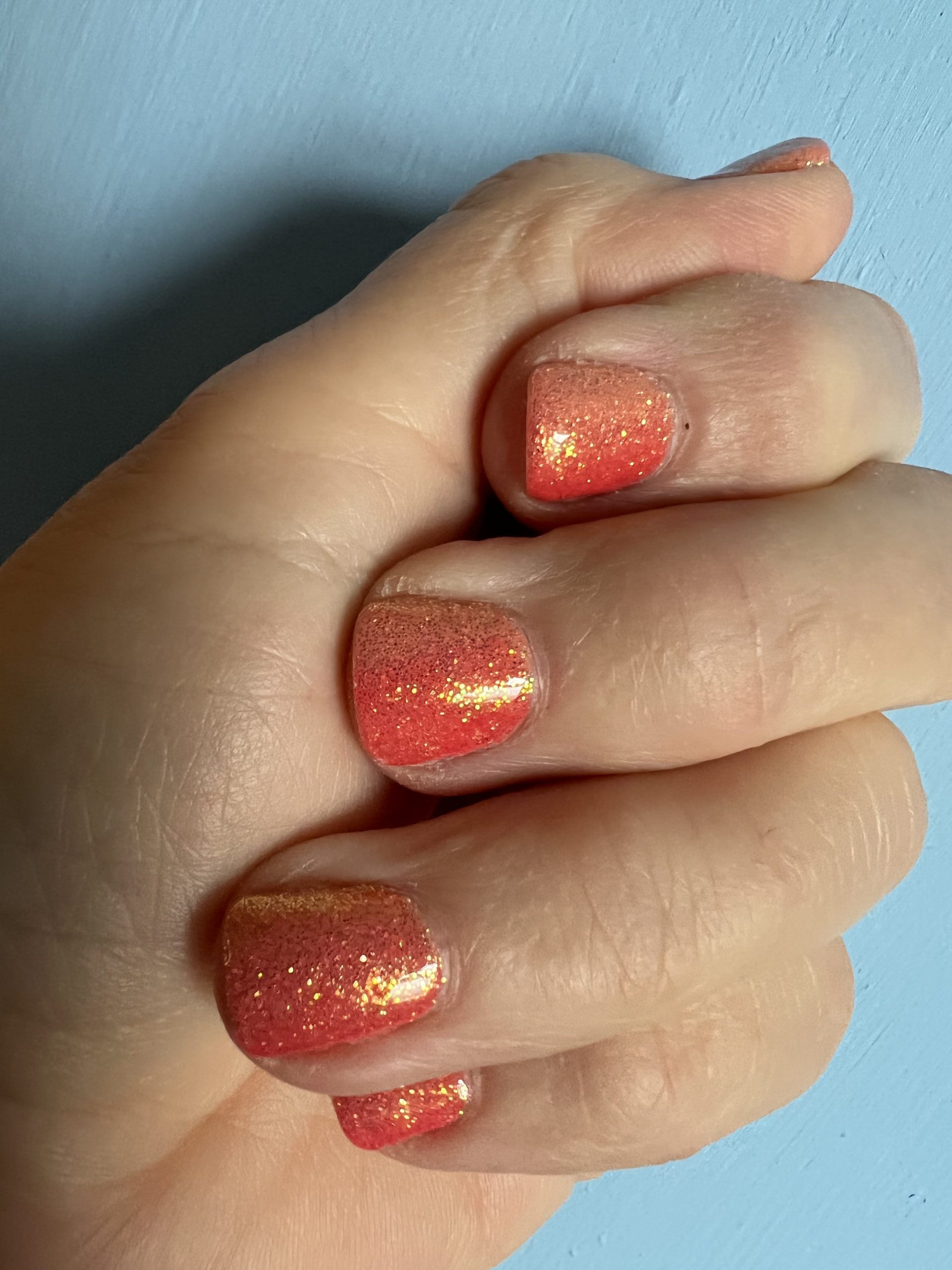 alt="hand with sparkly nail varnish on nails"