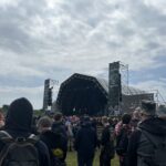 alt="crowd in front of a stage with clouds above"