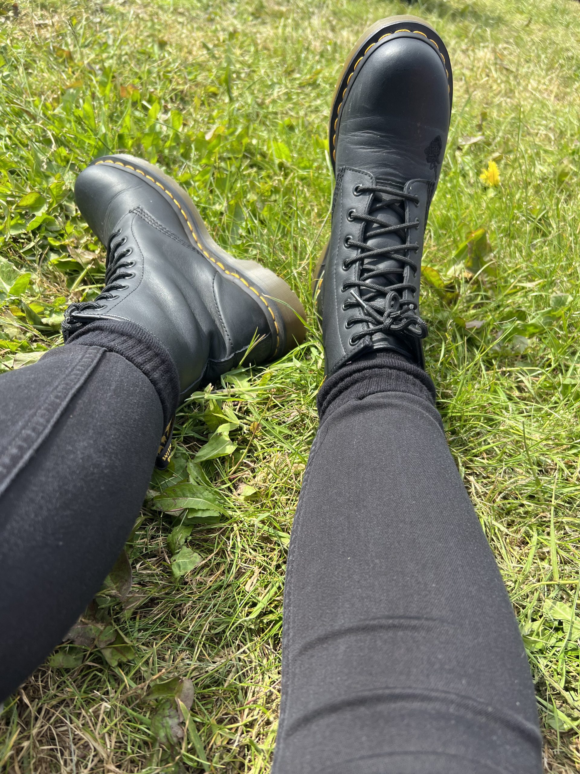 alt="two legs with black jeans & doc marten boots"