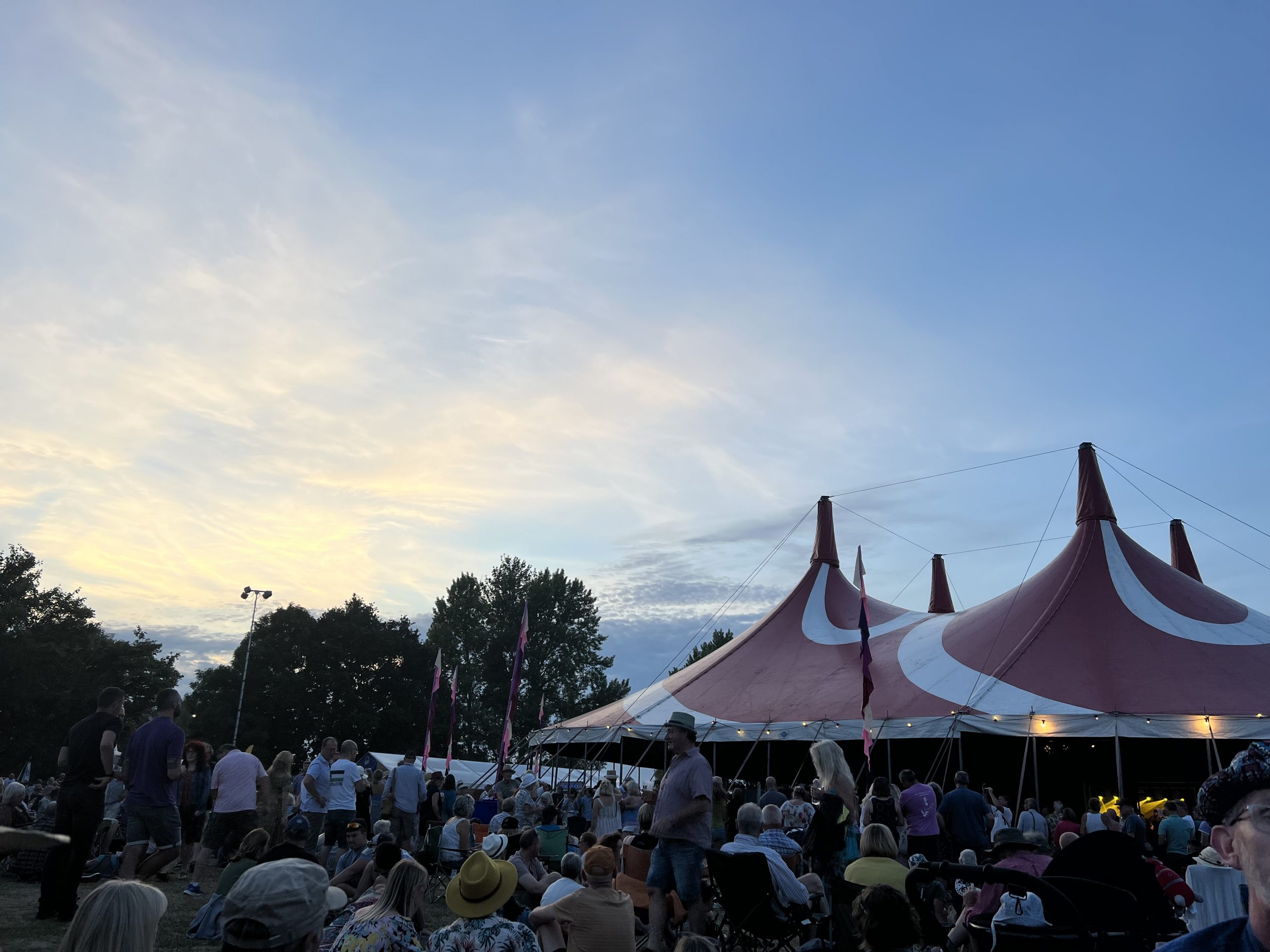 alt="big tents with people sat outside"
