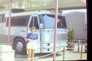 alt="person stood next to tour bus"