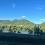 alt="water with trees & hills in background"