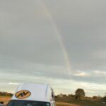 alt="roof of camper with rainbow behind it"