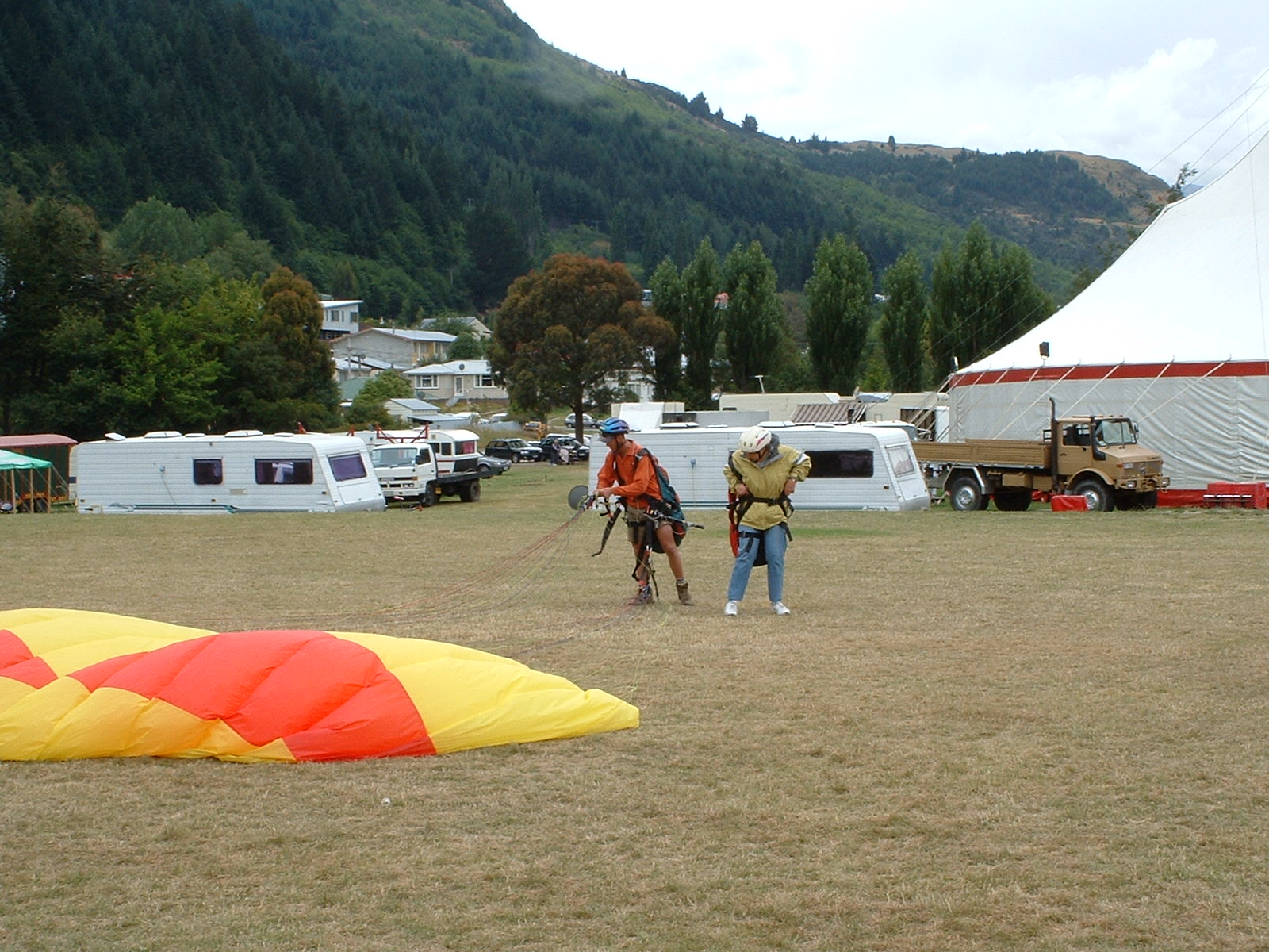 alt="paraglider on ground with two people"