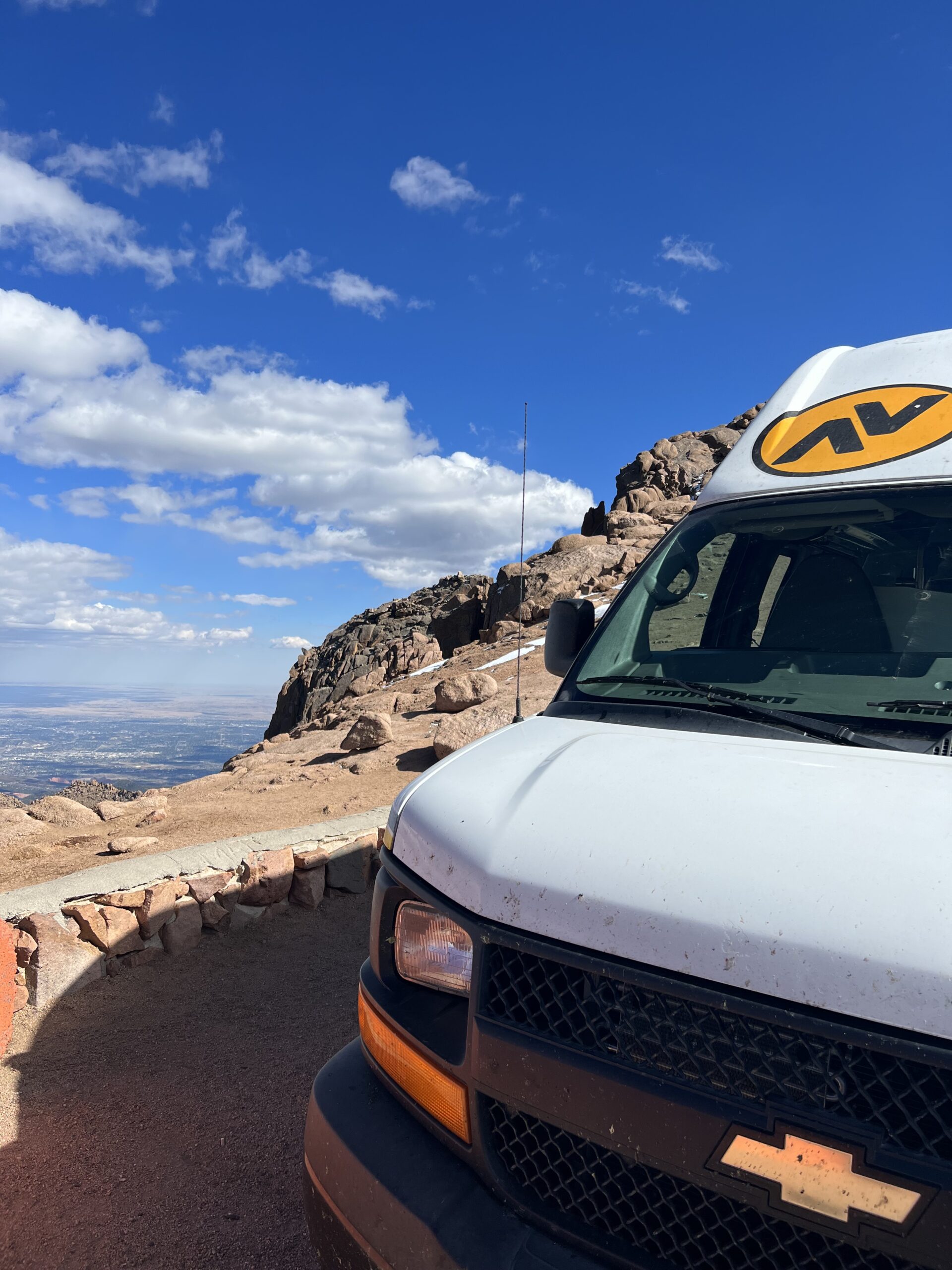 alt="van on edge of mountain with sky & clouds"