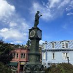 alt="clock with statue of person on top"