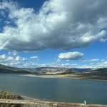 alt="open water with mountains & clouds"