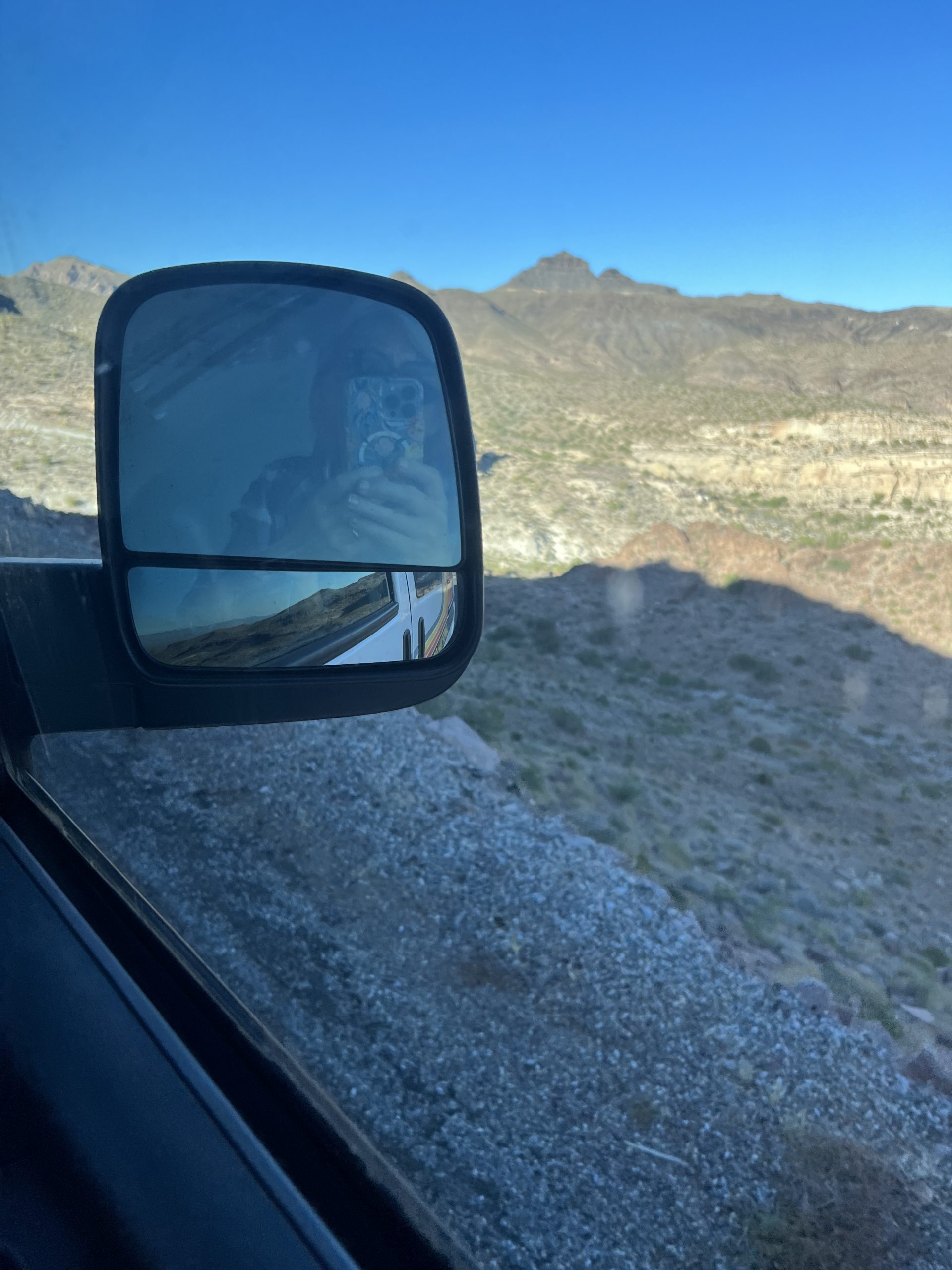alt="wind mirror of the van with view of mountain from side window"