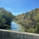 alt="a small river with trees on either bank"