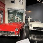 alt="two older models of cars in garage"