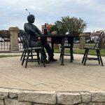 alt="statue of Doc Holiday sat at table"