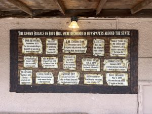 alt="various plaques commemorating those buried in the Boot Hill cemetery"