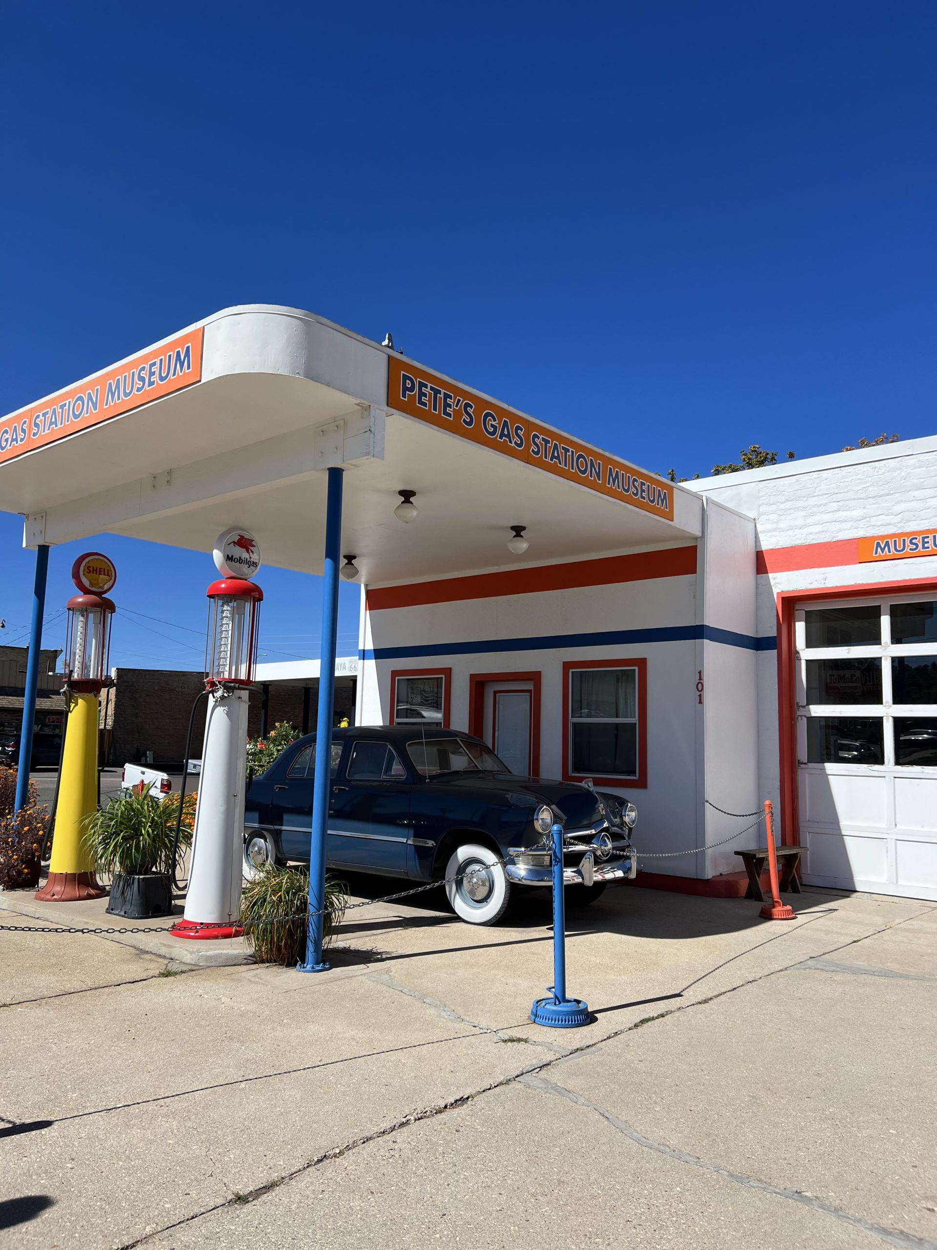 al="old fashioned car next to an old petrol pump"