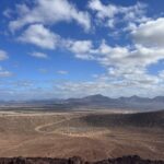 alt="the inside of a volcanic crater & hills in the background"