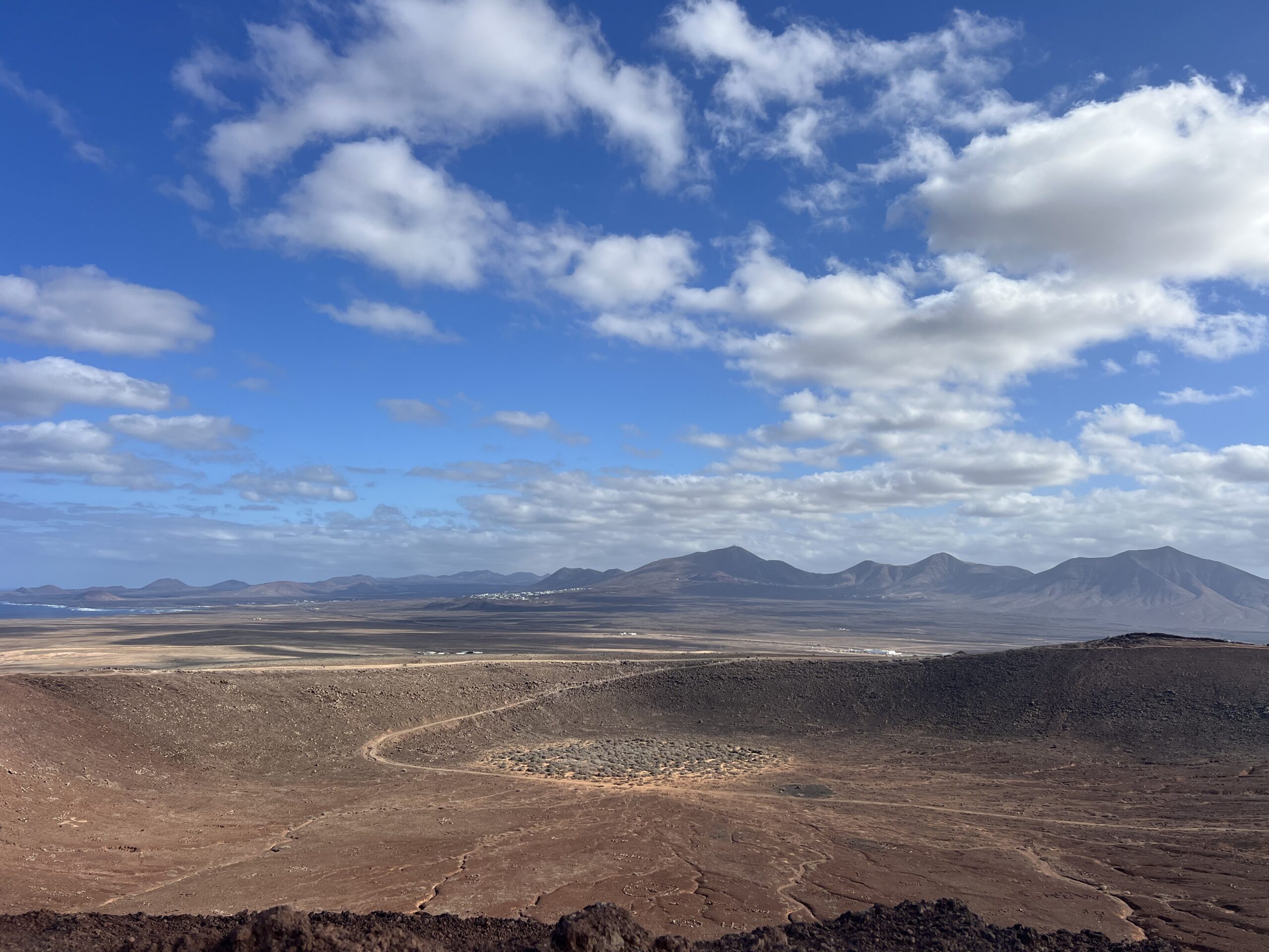 alt="the inside of a volcanic crater & hills in the background"