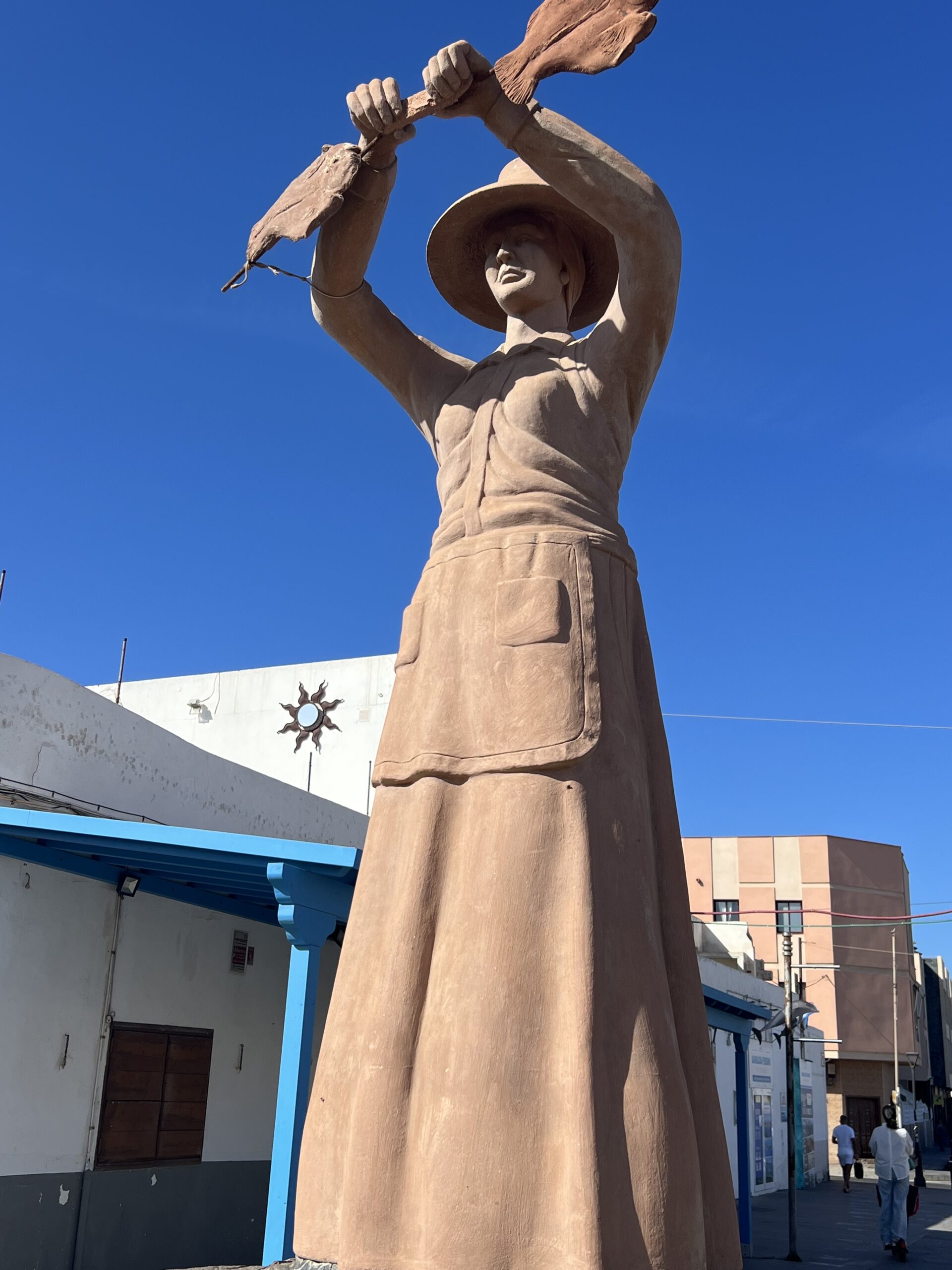 alt="statue of a woman with large hat holding leaves"