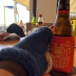 " my gloved hand reaching out to pick up a bottle of beer in insulated sleeve"