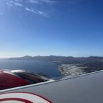 alt="the edge of an airplane wing & the ground below"
