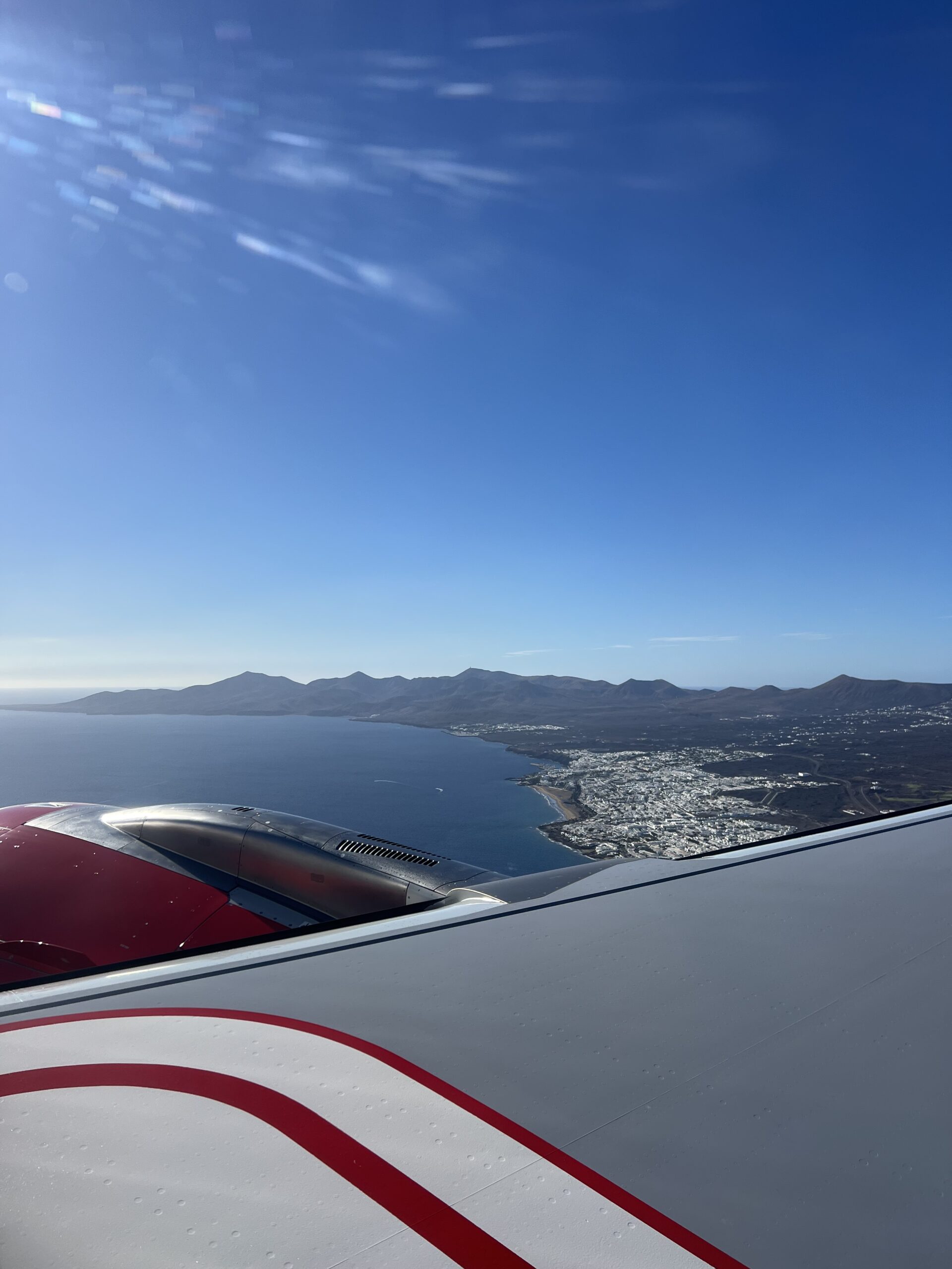 alt="the edge of an airplane wing & the ground below"