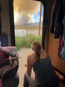 alt="person looking at the smoke filled sky from the camper van"