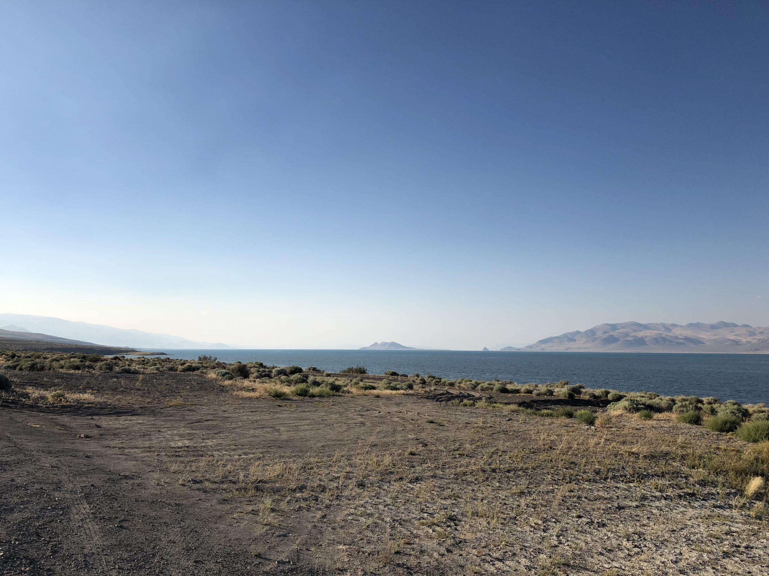 alt="sandy foreground with lake & mountains in background"