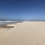 alt="sandy beach with blue sky & waves"