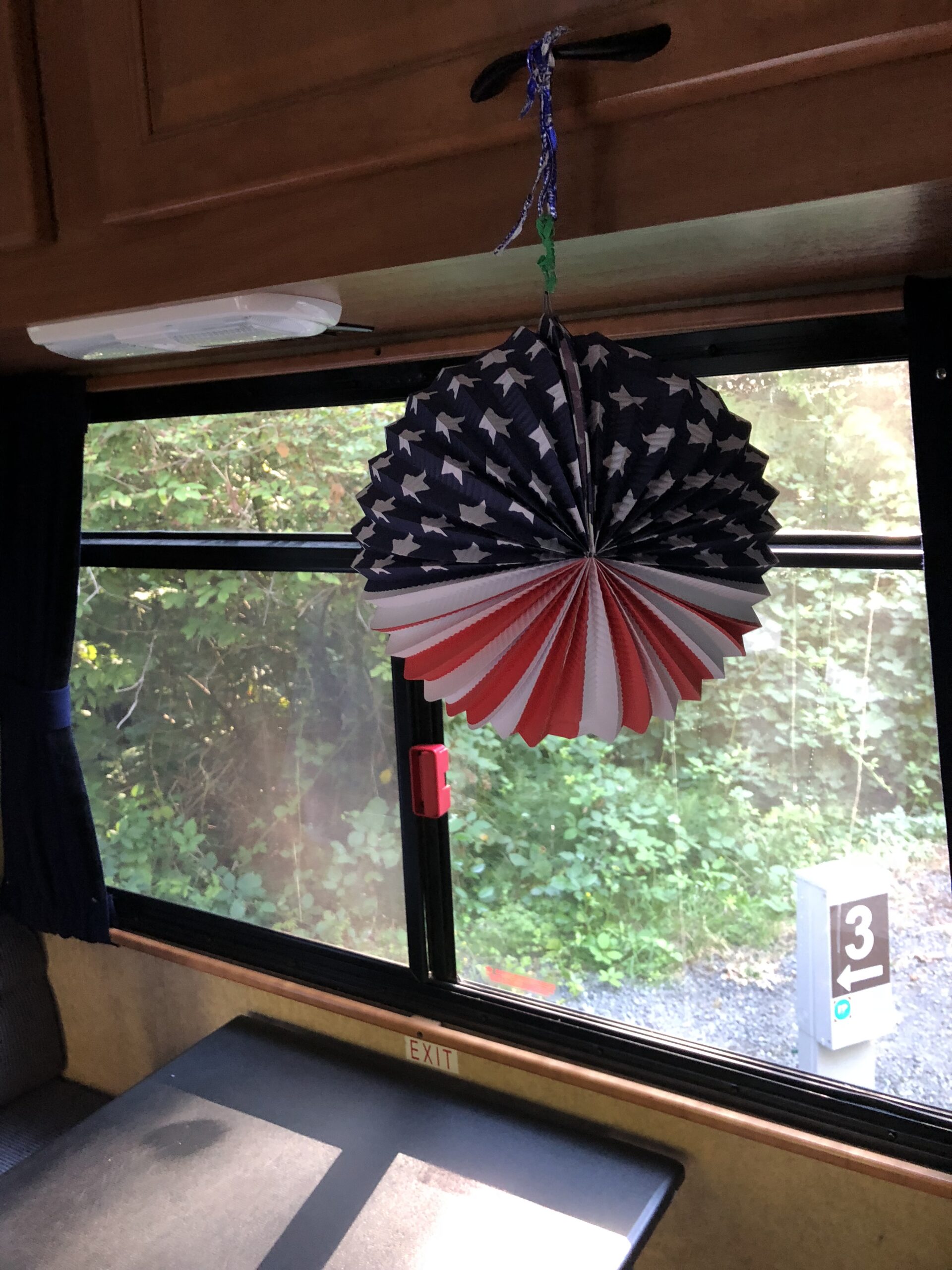 alt=a"paper decoration with the american flag hanging in RV window"