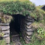 alt="small entrance to structure with grass roof"