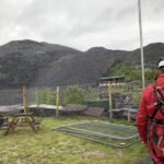 alt=" a person in safety harness with quarry slopes in background"