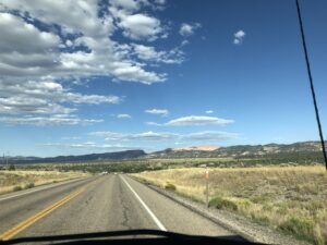 alt="road with mountains in distance & unusual clouds"