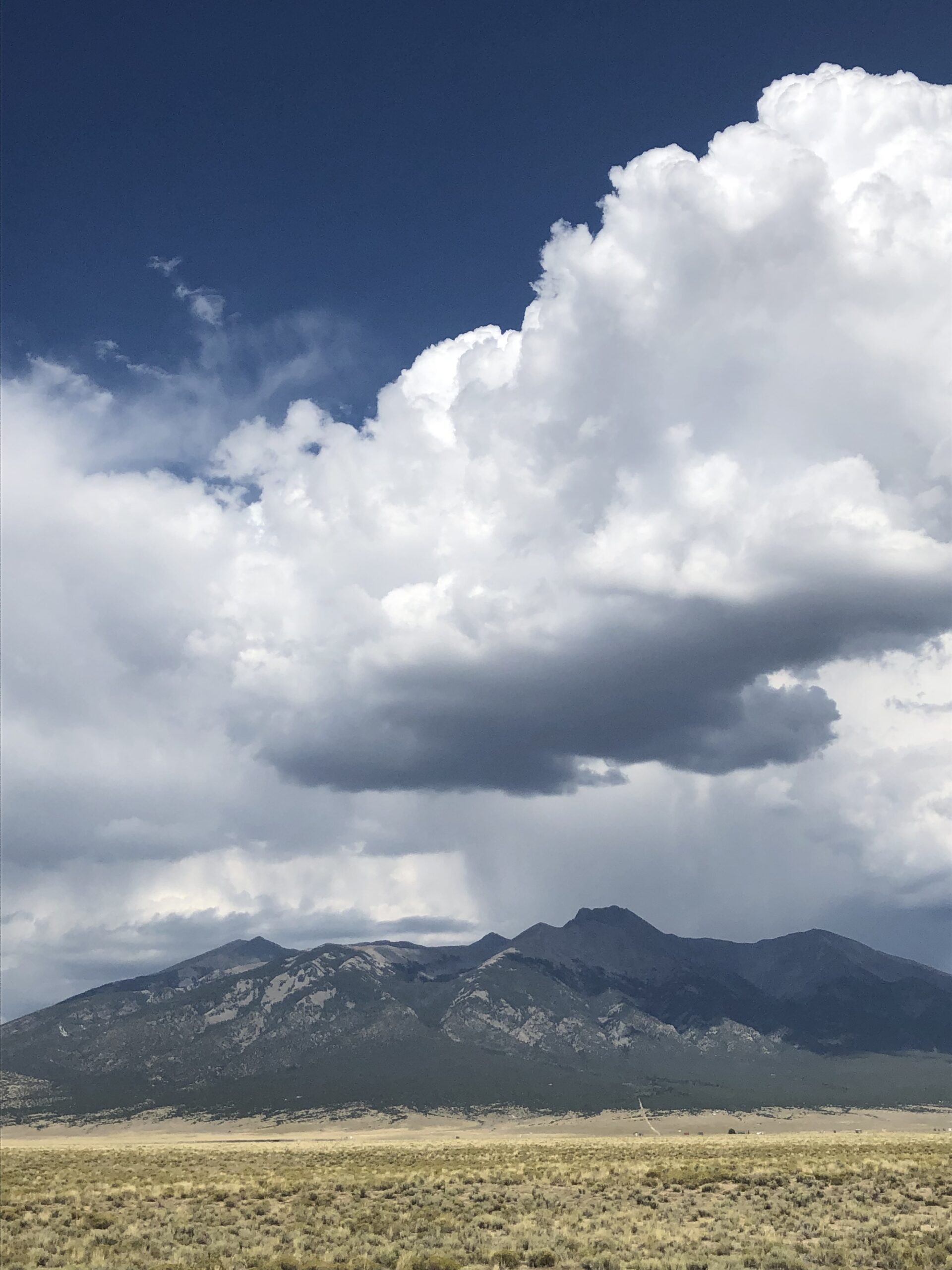 alt="large cloud with sand dunes in background"
