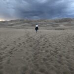 alt="person walking towards sand dune"