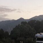 alt="campervan with trees & mountains in background"