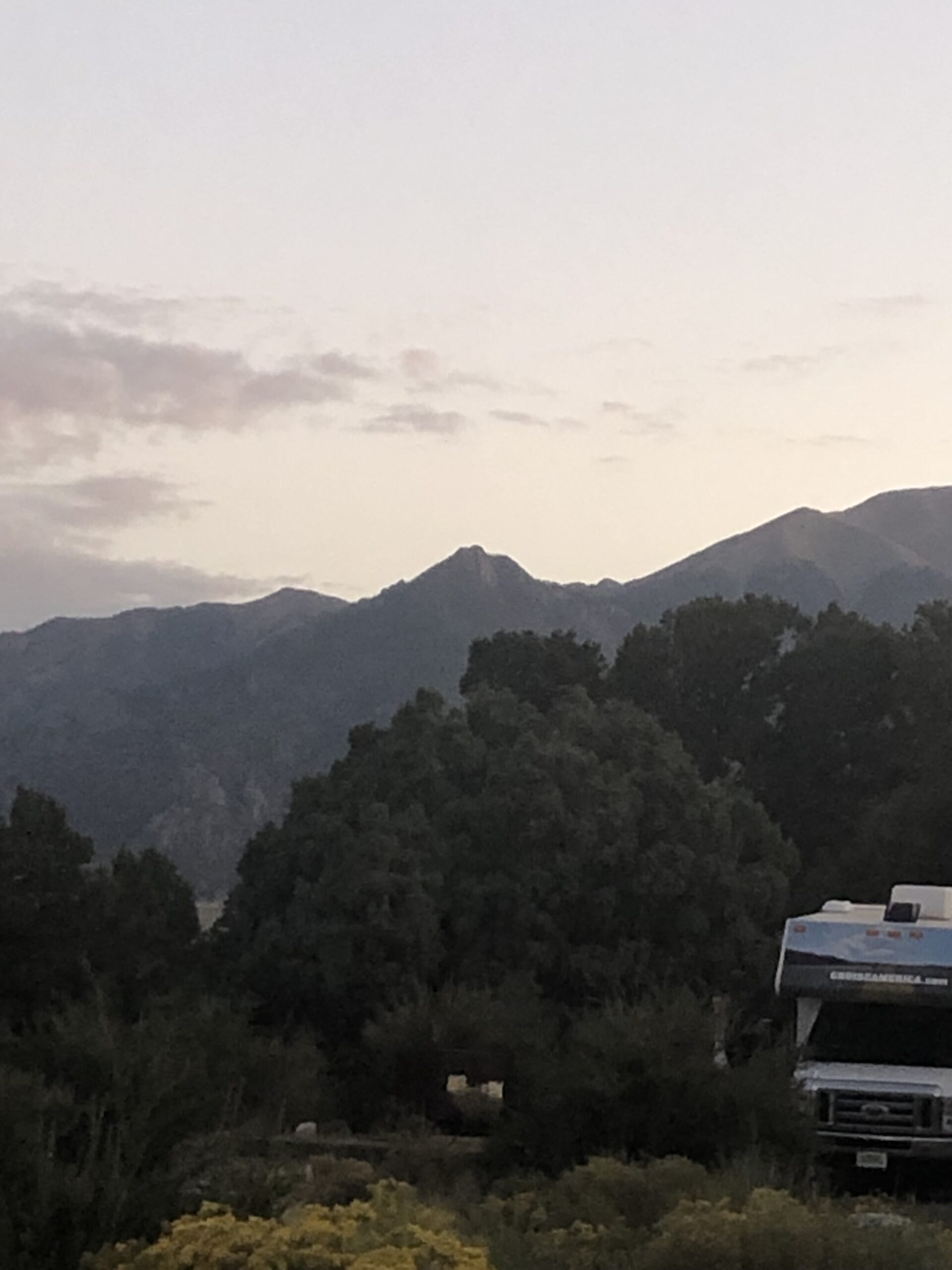 alt="campervan with trees & mountains in background"